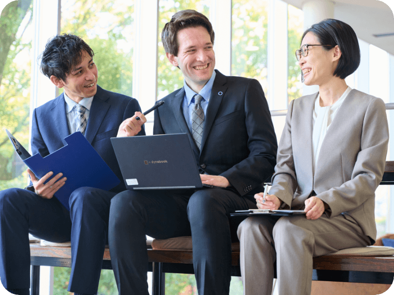 Three men and women having a meeting while looking at a PC in a free space