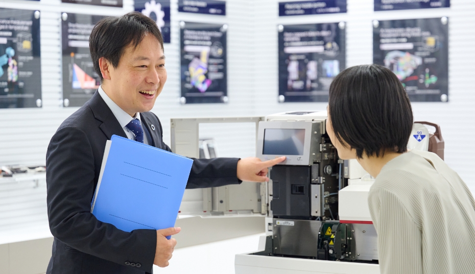 男性と女性が笑顔で装置について話している様子